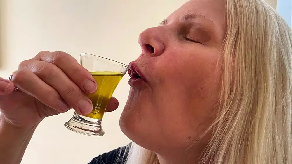 Nő egy kis pohárból meleg, aranyszínű italt iszik